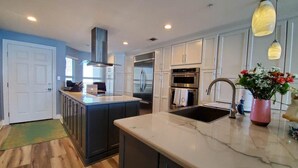 A modern kitchen with a central island, stainless steel appliances, and pendant lighting.