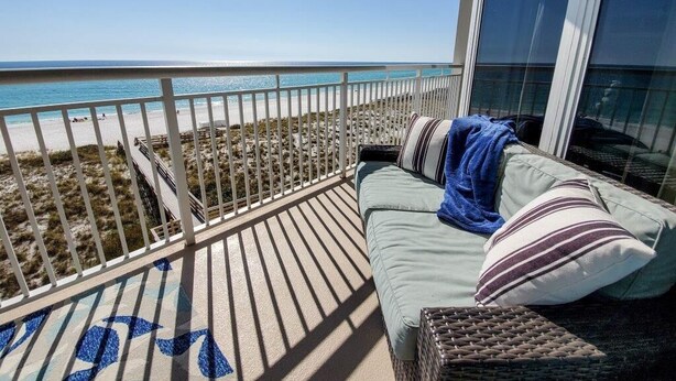 A balcony with a view of the beach and ocean.