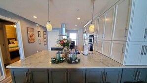 A modern kitchen with a central island, bar stools, and pendant lighting.
