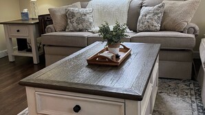 A cozy living room with a sofa, a coffee table, a lamp, and a painting on the wall. - Cute & cozy, close to downtown Boyne city!  (Boyne City)