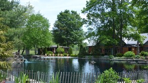 A serene pond with a wooden fence, surrounded by lush greenery and trees. - Scottland Yard Farm's - Upscale Rustic Garden House (Brooktondale)