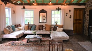 A cozy living room with a sectional sofa, a coffee table, and a fireplace. - Scottland Yard Farm's - Upscale Rustic Garden House (Brooktondale)