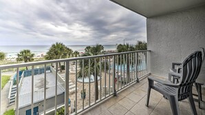 A balcony with a view of the ocean, a pool area, and a chair. - PCB Condo w/ 2 Outdoor Pools & Beach Access! (Panama City)
