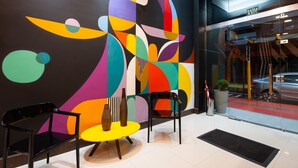 Un interior moderno con arte abstracto en la pared, una recepción y una puerta de vidrio que da al exterior.