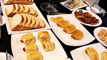 A buffet with various food items including bread, pastries, and fruits.
