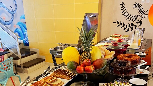 Una mesa de bufé con diversas opciones de comida, incluyendo frutas, pasteles y postres.