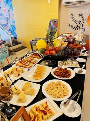 Una mesa de bufé con diversas opciones de comida, incluyendo frutas, pasteles y postres.