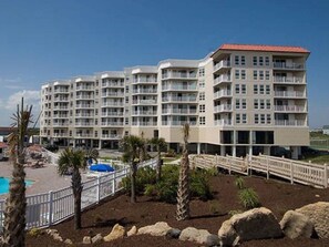 A multi-story hotel with balconies, a swimming pool, and landscaped grounds.