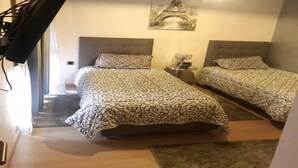 Een slaapkamer met twee bedden, een nachtkastje, een lamp en een afbeelding van de Eiffeltoren aan de muur.