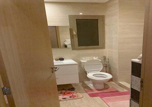 Een badkamer met toilet, wastafel en spiegel.