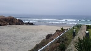A beach with a rocky outcrop and a clear view of the ocean. - Modern Ocean View  Condo with Private  Beach   (PLAYAS encantada, playa de Rosarito)