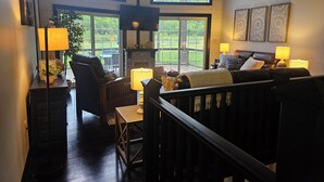 A spacious living room with a fireplace, large windows, and a view of the outdoors. - Name: Hill Side<br>Country Setting. Heated Pool.  4 minutes to Dreams Park. (Cooperstown)