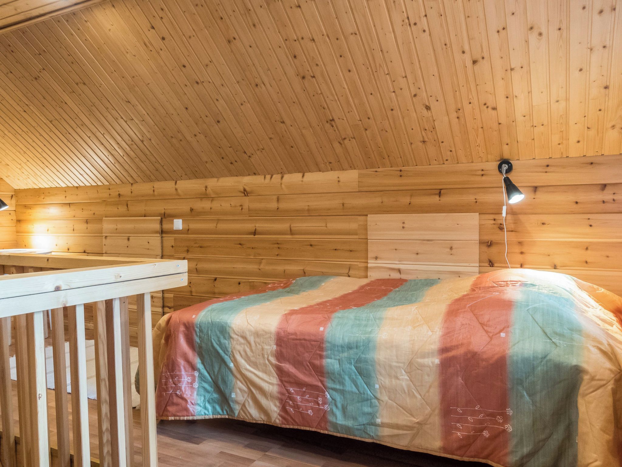Une pièce de cabane en bois comprenant un lit, une petite table et un plafond en pente.
