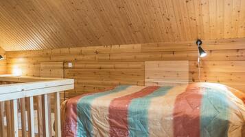 Une pièce de cabane en bois comprenant un lit, une petite table et un plafond en pente.