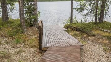 Een houten steiger die uitkomt bij een rustig meer, omringd door bomen.
