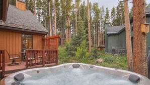 Ett bubbelbad omgivet av ett trädäck, med utsikt över ett skogsområde.