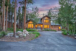 A two-story house with a garage, surrounded by tall trees and a driveway. - 4BR Breck Home, Private Hot Tub, Sleeps 12 (Breckenridge)