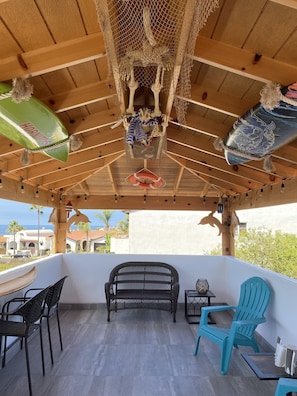Un espace extérieur abrité, doté d’un plafond en bois, d’un hamac, d’un banc et de chaises.