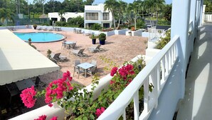 A pool area with lounge chairs and tables, surrounded by a white fence and potted plants. - Resort style vacation, 2BR/2BA condo in the heart of Naples: 8min to the beach (Naples)