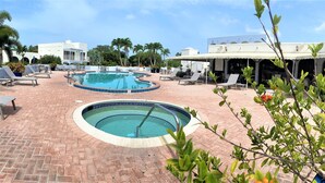 A pool area with two circular pools, lounge chairs, and a covered seating area. - Resort style vacation, 2BR/2BA condo in the heart of Naples: 8min to the beach (Naples)