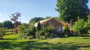 Un petit bâtiment d’un seul étage, doté d’un toit à deux versants, et entouré d’une végétation luxuriante et d’arbres.
