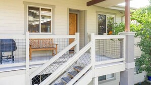 A covered outdoor area with a wooden bench, a grill, and a staircase with a railing.