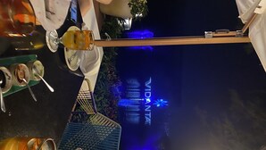 A dining area with tables, chairs, and a view of the 'VIDANTA' sign illuminated in the background. - Vidanta Luxury Paradise by (Nuevo Vallarta)