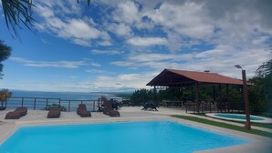 Un espace piscine doté de chaises longues et d’un belvédère offrant une vue panoramique.