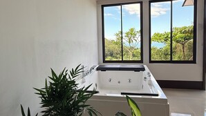 Une salle de bain moderne avec une baignoire, de grandes fenêtres et une plante en pot.