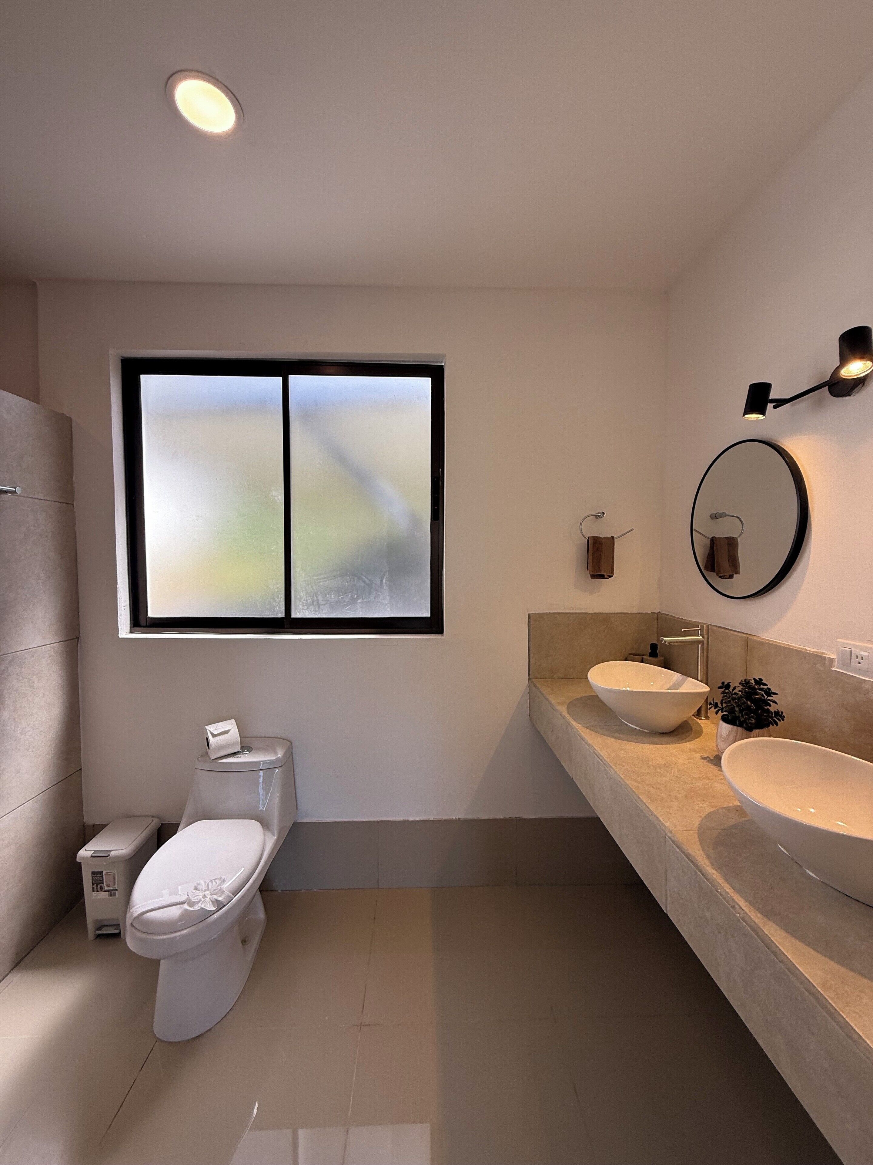 Un bagno moderno con un water, un bidet e due lavandini con uno specchio grande sopra.