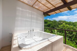 A large, white freestanding bathtub on a balcony with a view of lush greenery. - Villas Azul (Tárcoles)