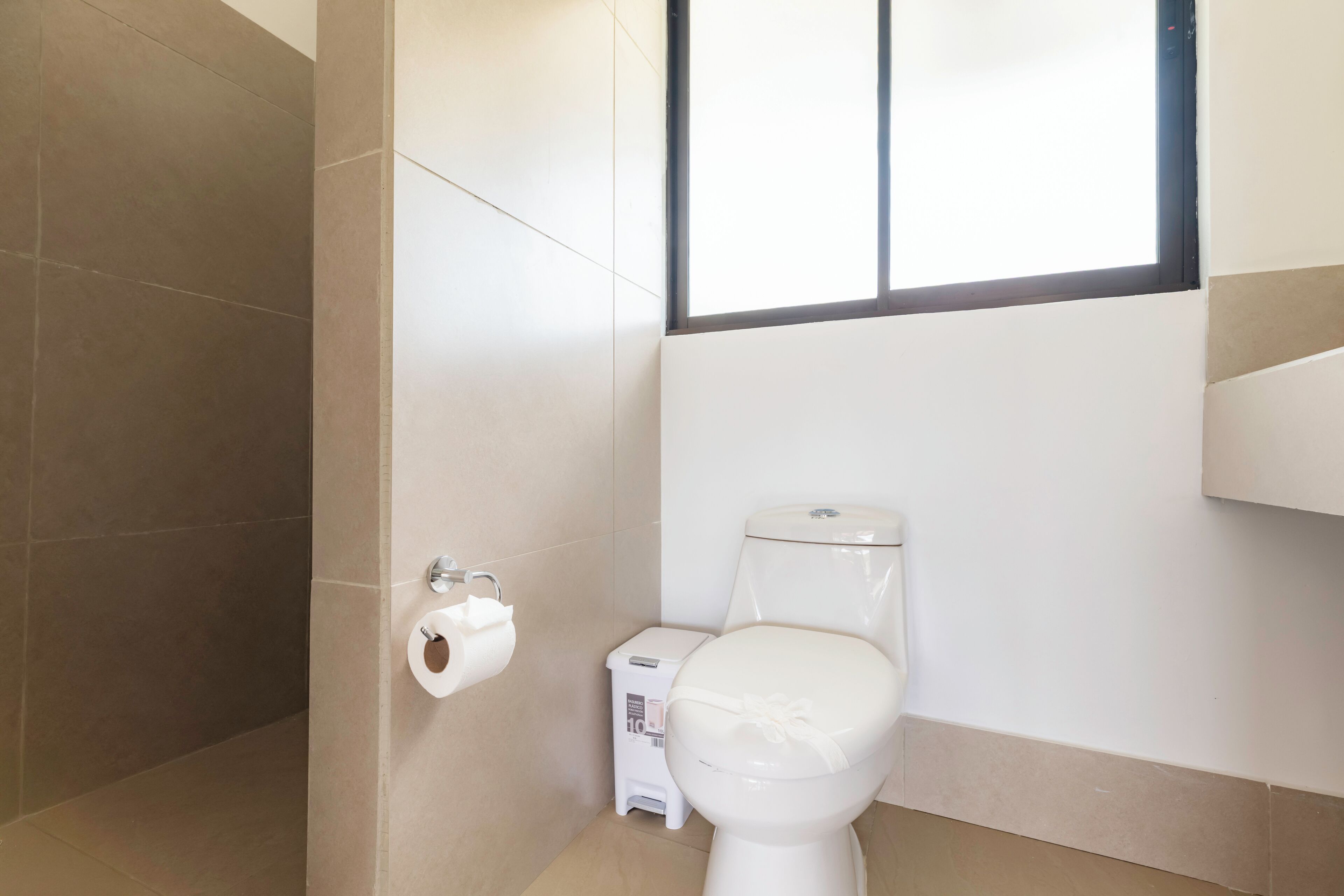 A bathroom with a toilet, a paper towel dispenser, and a small trash bin.