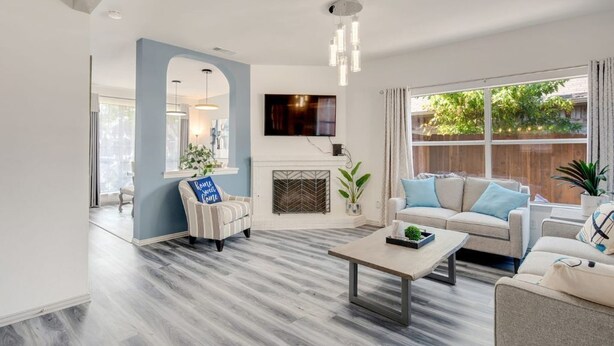 A modern living room with a fireplace, two sofas, a coffee table, and a TV mounted on the wall. - Stylish House w playset ,Game room &BBQ near DFW airport ,Gaylord sleeps 10-14 (Flower Mound)