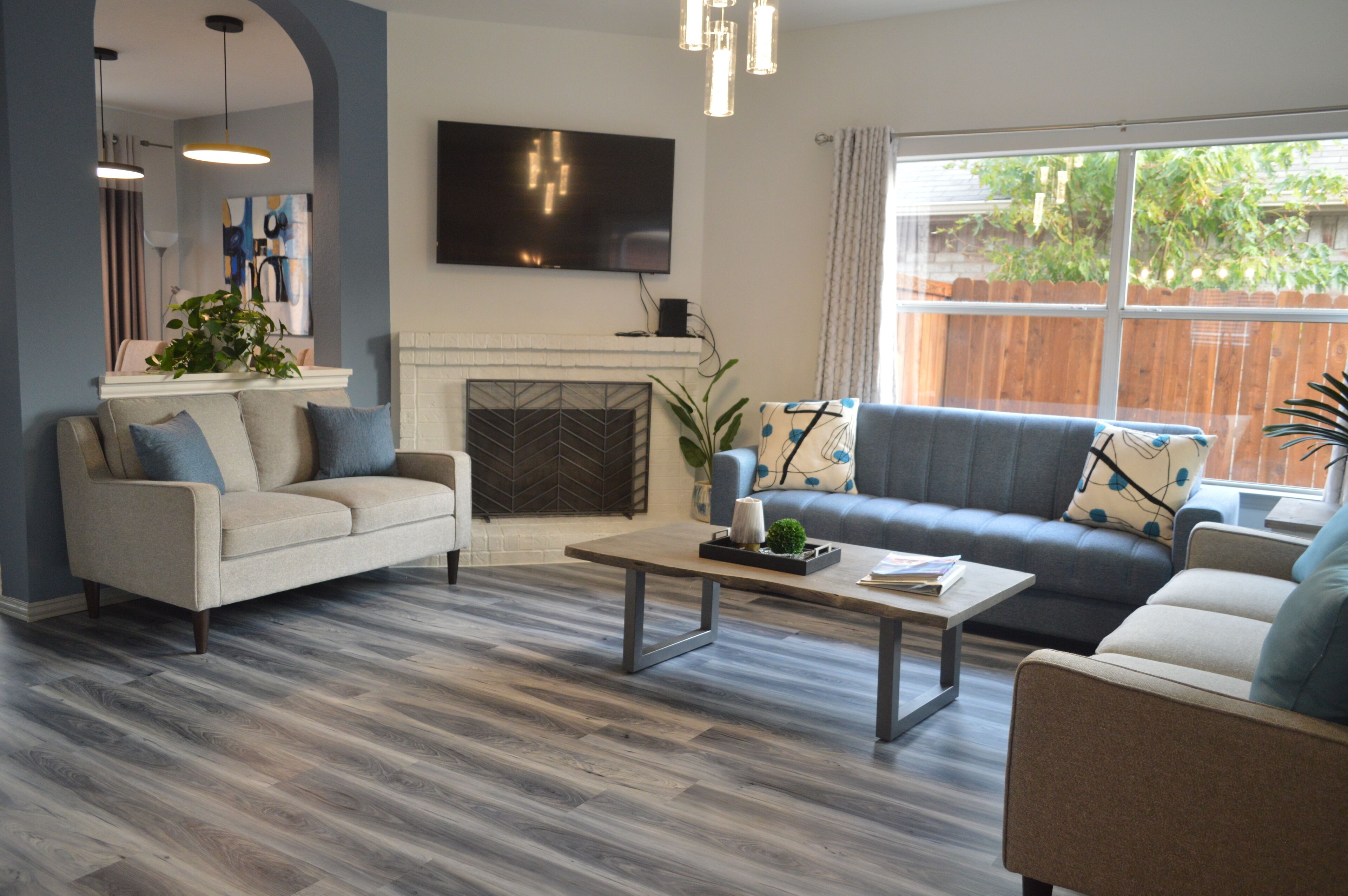 A living room with a fireplace, two sofas, a coffee table, and a TV mounted on the wall.