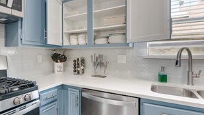 A kitchen with blue cabinets, a stainless steel dishwasher, and a gas stove. - Stylish House w playset ,Game room &BBQ near DFW airport ,Gaylord sleeps 10-14 (Flower Mound)