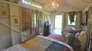 A room with a large bed, a chandelier, and a view of the outdoors.