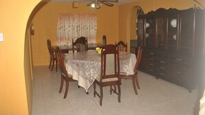 Una sala da pranzo con un tavolo rotondo, sedie, una ventola a soffitto e un armadio.