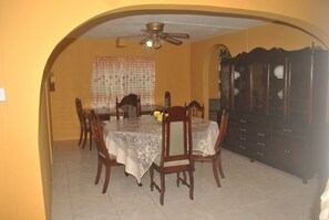 A dining room with a round table, chairs, a ceiling fan, and a cabinet. - Superb Villa in Montego Bay (Montego Bay)