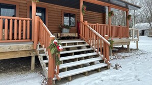 A wooden cabin with a porch, steps, and railings.