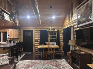 L’intérieur d’une cabane en rondins comprend un coin repas, une cuisine et un grand téléviseur à écran plat.