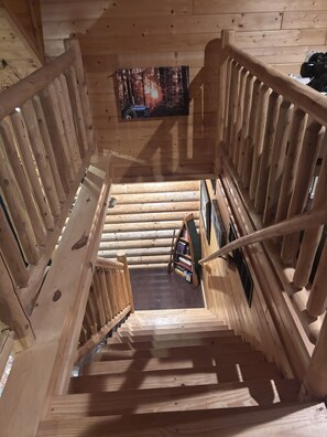 Una escalera de madera con una estantería y un cuadro enmarcado en la pared.