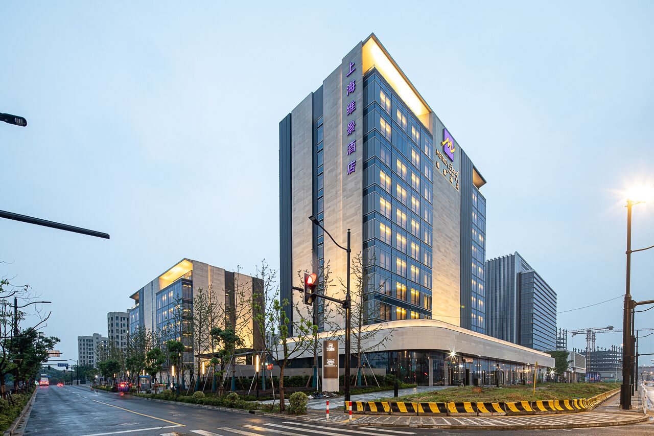 A modern hotel with a prominent vertical sign, multiple floors, and a well-lit facade.