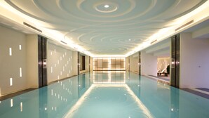 Una amplia piscina interior con un diseño moderno de techo e iluminación empotrada.