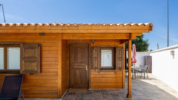 Un edificio de madera con patio empedrado, una puerta y una ventana.