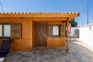 A wooden building with a tiled patio, a door, and a window. - Casa Rural 'La Dehesilla' in Toledo – Cozy Retreat for 4 with Private Plot (Cobisa)