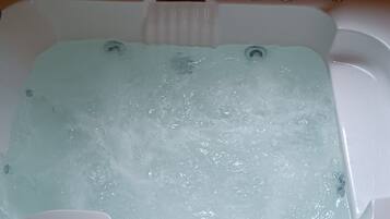 A bathtub filled with water, a wooden panel wall, and a faucet.