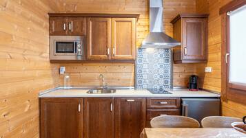 Cocina compacta con armarios de madera, un microondas de acero inoxidable, un fregadero y una cafetera.