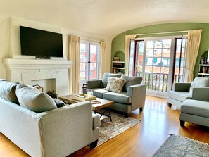 A living room with a fireplace, sofas, a coffee table, and a television. - Quincy La Casa (Long Beach)