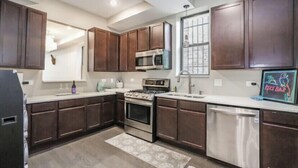 A modern kitchen with dark wooden cabinets, stainless steel appliances, and a tiled backsplash. -  LakeHouse with rooftop and views of lake. (Chicago)