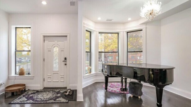 A room with a grand piano, a chandelier, and large windows with a view of the outside. -  LakeHouse with rooftop and views of lake. (Chicago)